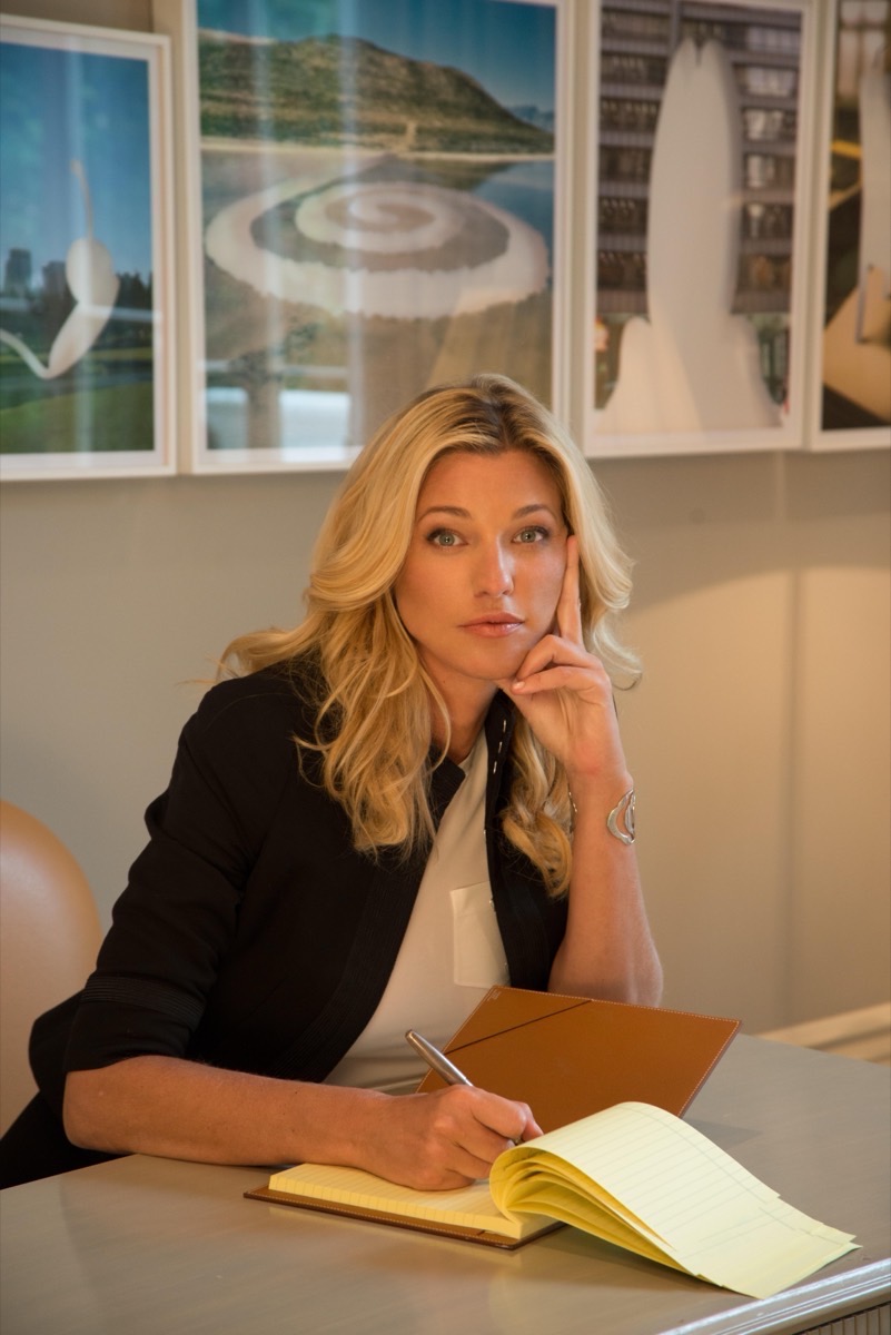 Nicole Junkermann in a black blazer writing thoughtfully in a notebook at her desk