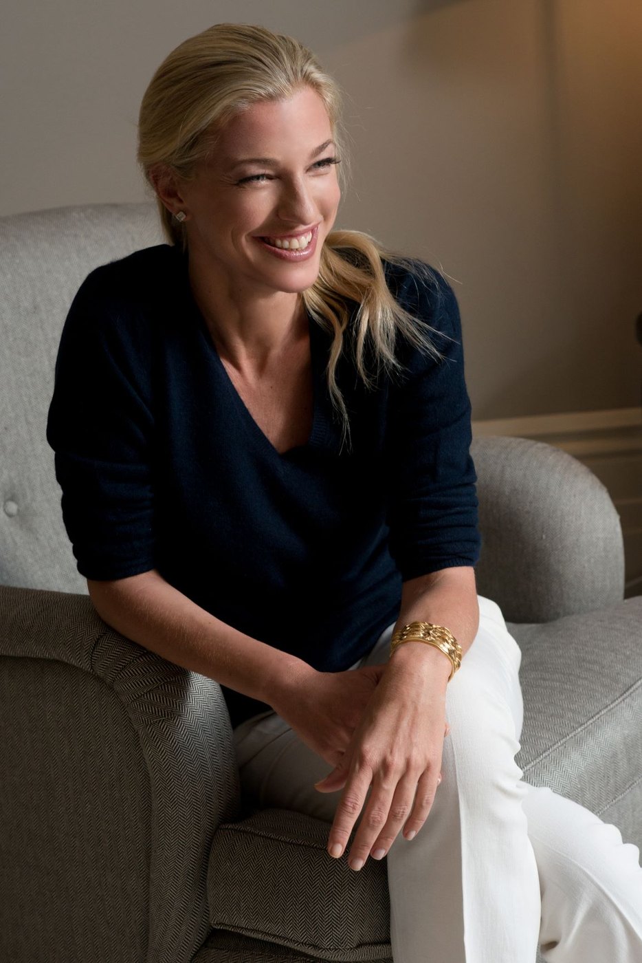 Nicole Junkermann seated on a navy sofa in a bright room, looking towards the camera