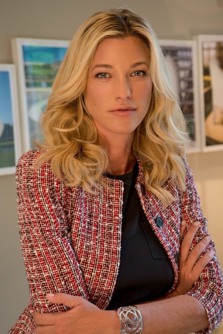 Nicole Junkermann in a textured jacket standing in a bright room with framed pictures behind her, a colour portrait
